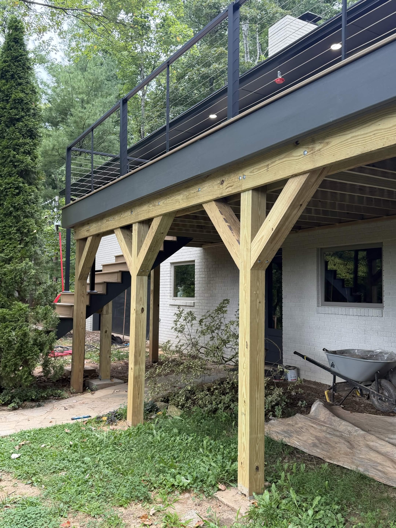 Structure under the deck: posts, beams, and stairs on a wooded Asheville lot — built by Terra Builders AVL